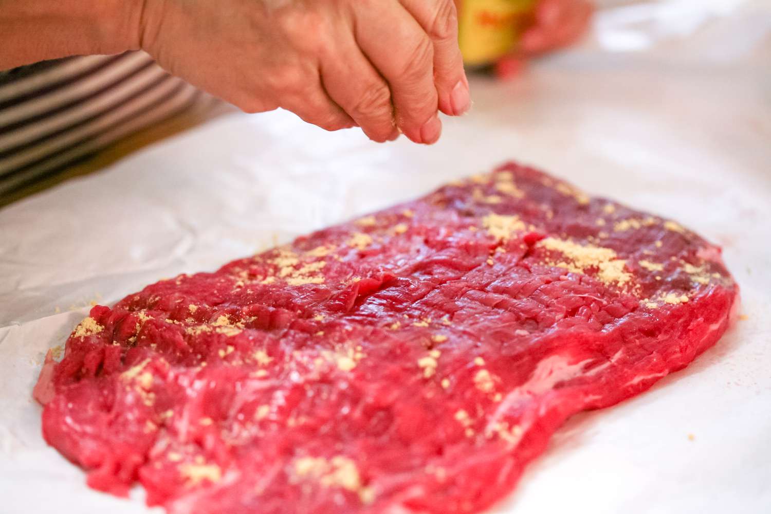 Seasoning flank steak for a steak recipes pan.