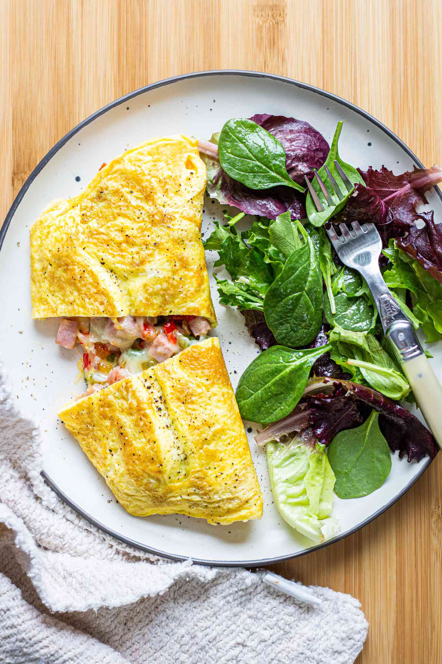 Denver Omelet Halved with Mixed Greens on Plate with Fork 