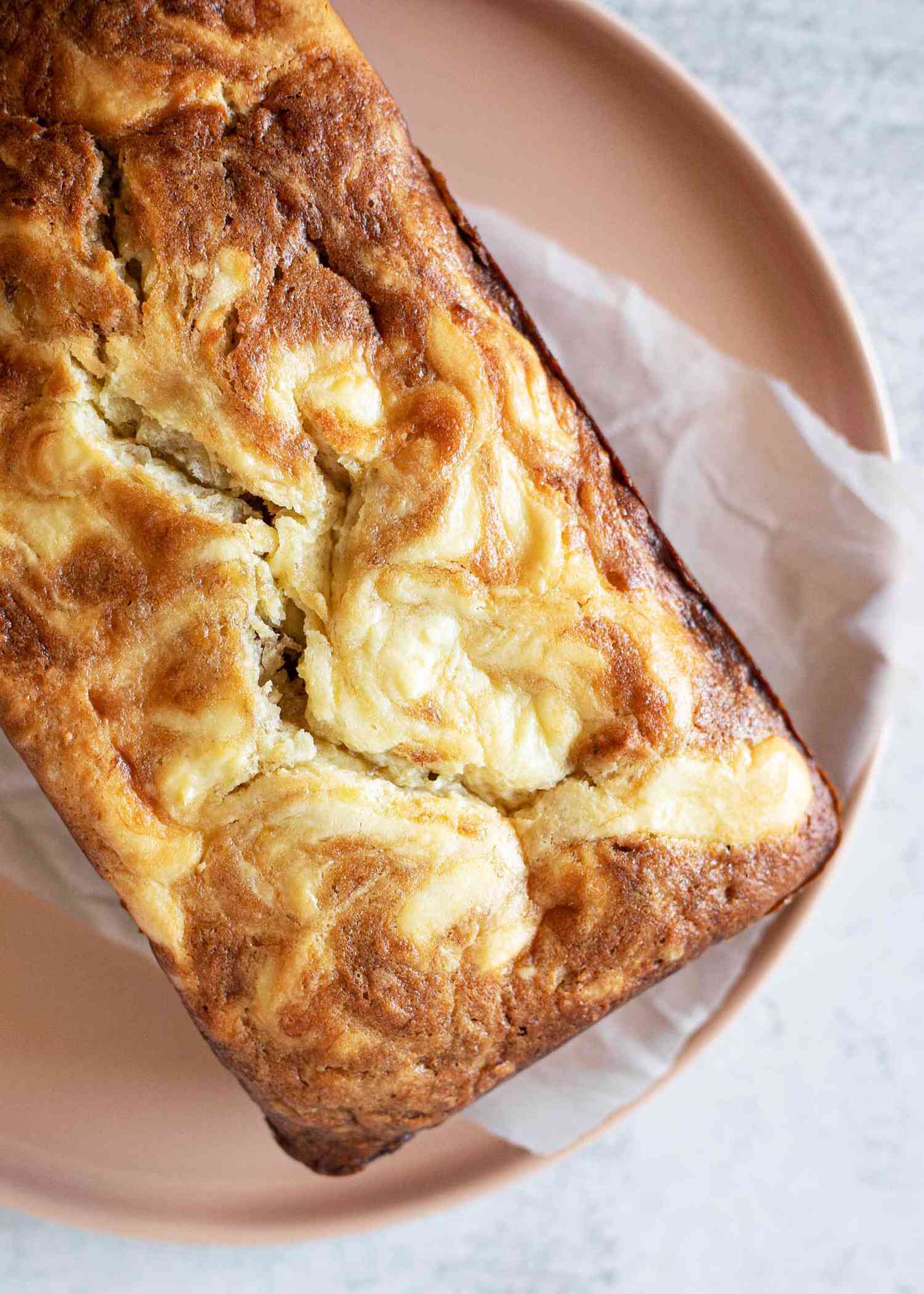 Overhead view of a loaf of cream cheese filled banana bread on a plate.