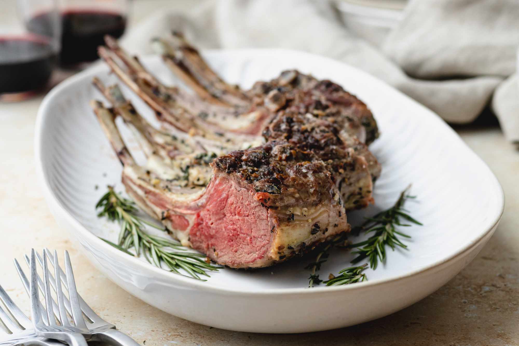 Rack of lamb cut into chops on platter with rosemary