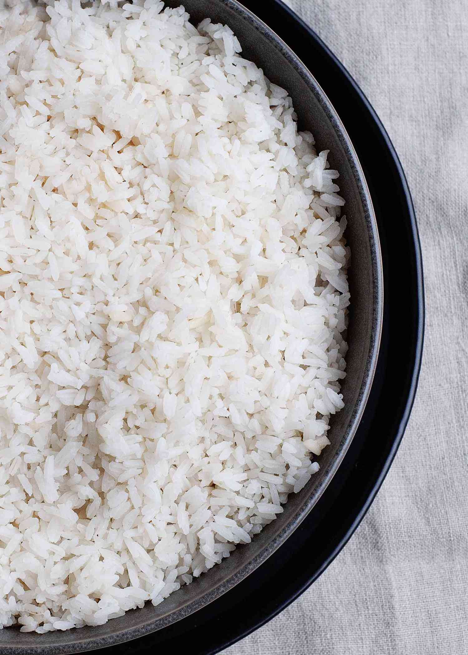 Perfect white rice in a metal pan set in a deep tray.