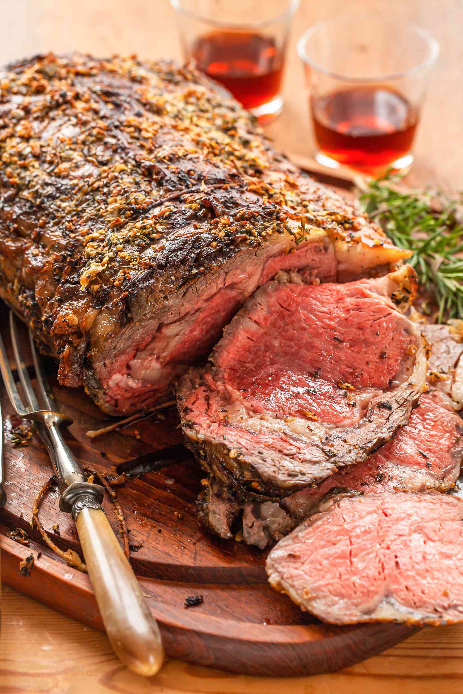 Prime Rib with Thyme, Rosemary, Shallot Herb Butter sliced on a cutting board.
