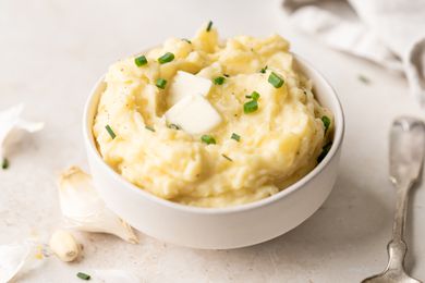 A bowl of roasted garlic mashed potatoes topped with a pat of butter.