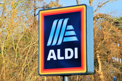 Image of a stand-alone Aldi grocery store sign with trees and power lines in the background
