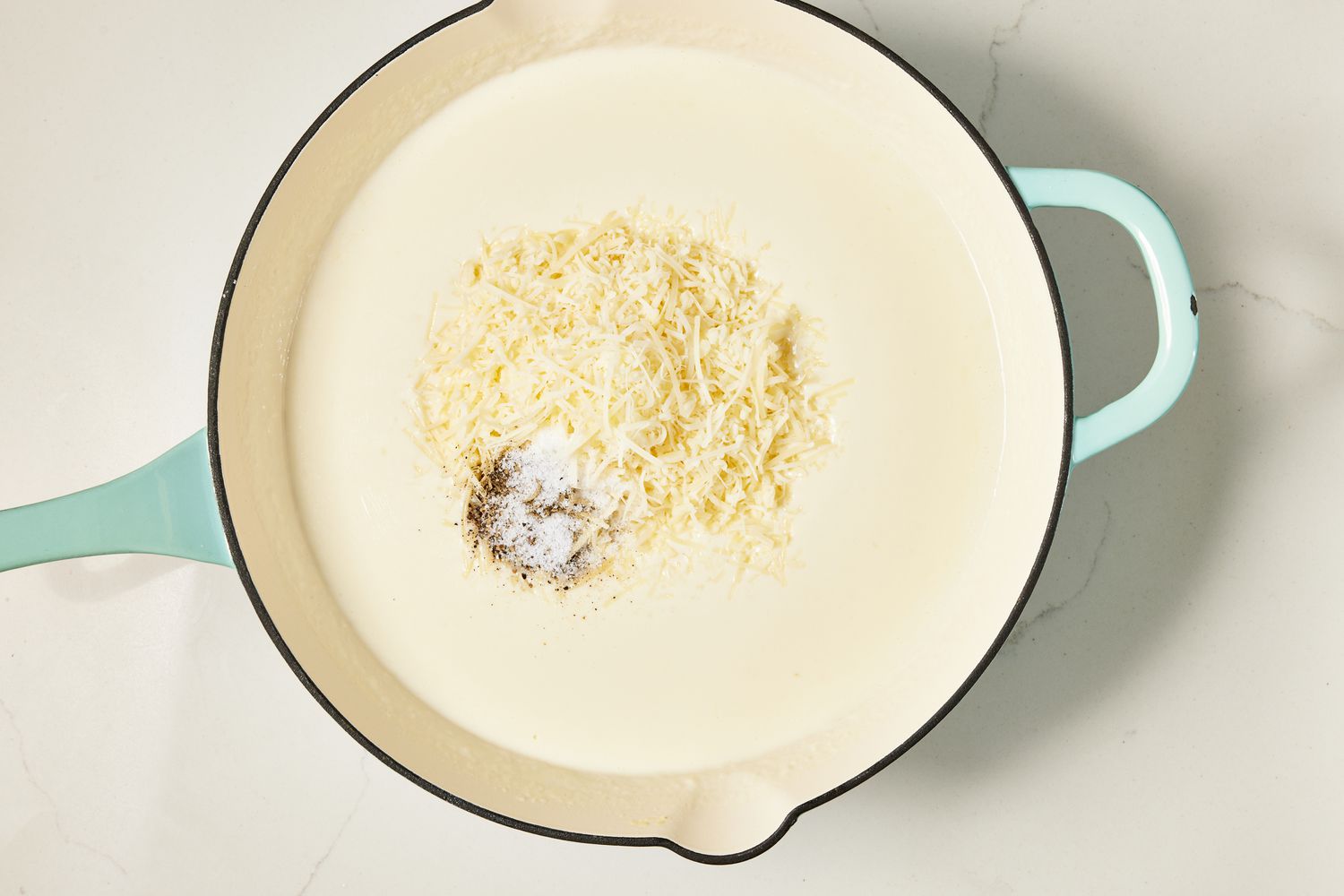 Parmesan and seasoning added to the sauce in the skillet for copycat Olive Garden Alfredo recipe 