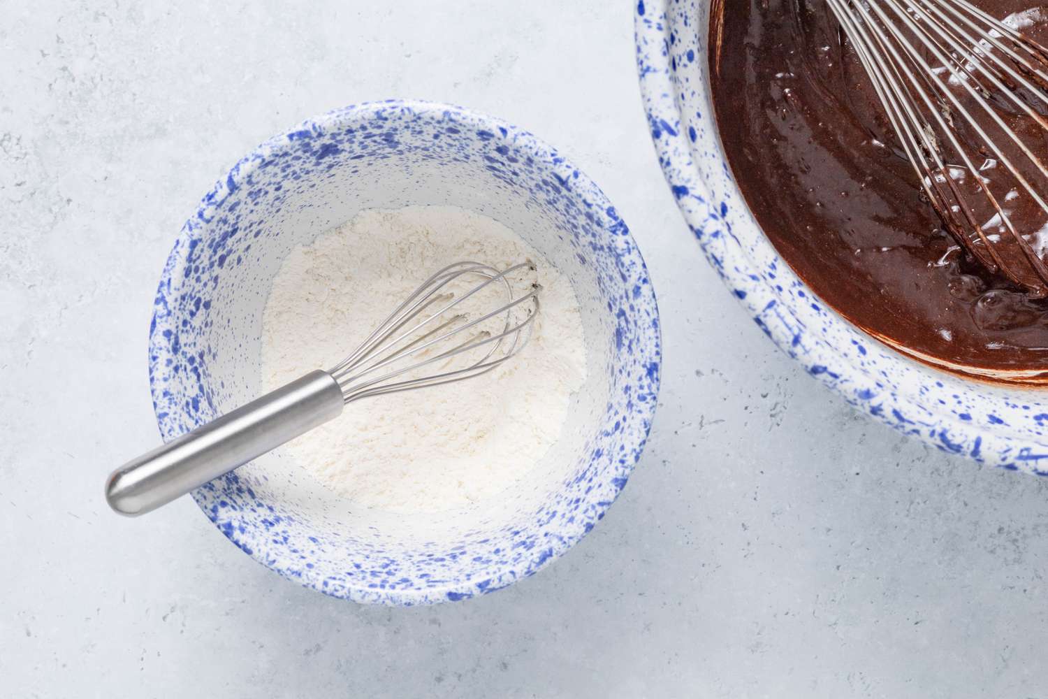 Two bowls (L to R): bowl with dry ingredients and bowl of wet ingredients, each bowl has a whisk