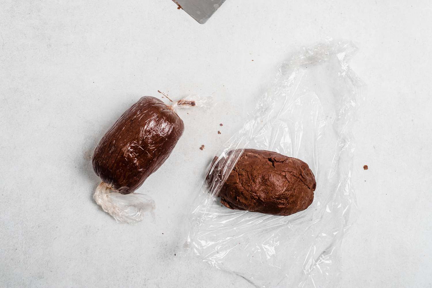 Two rolls of dough wrapped in plastic wrap for tender chocolate butter cookies.