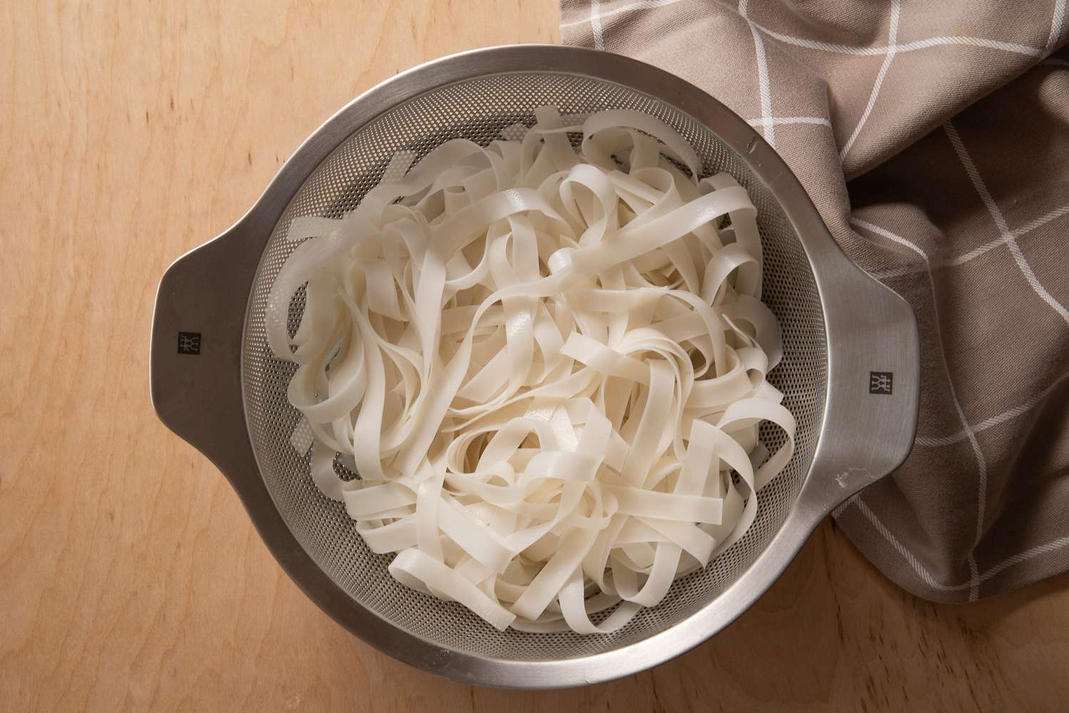 rice noodles in a colander for pad see ew recipe 