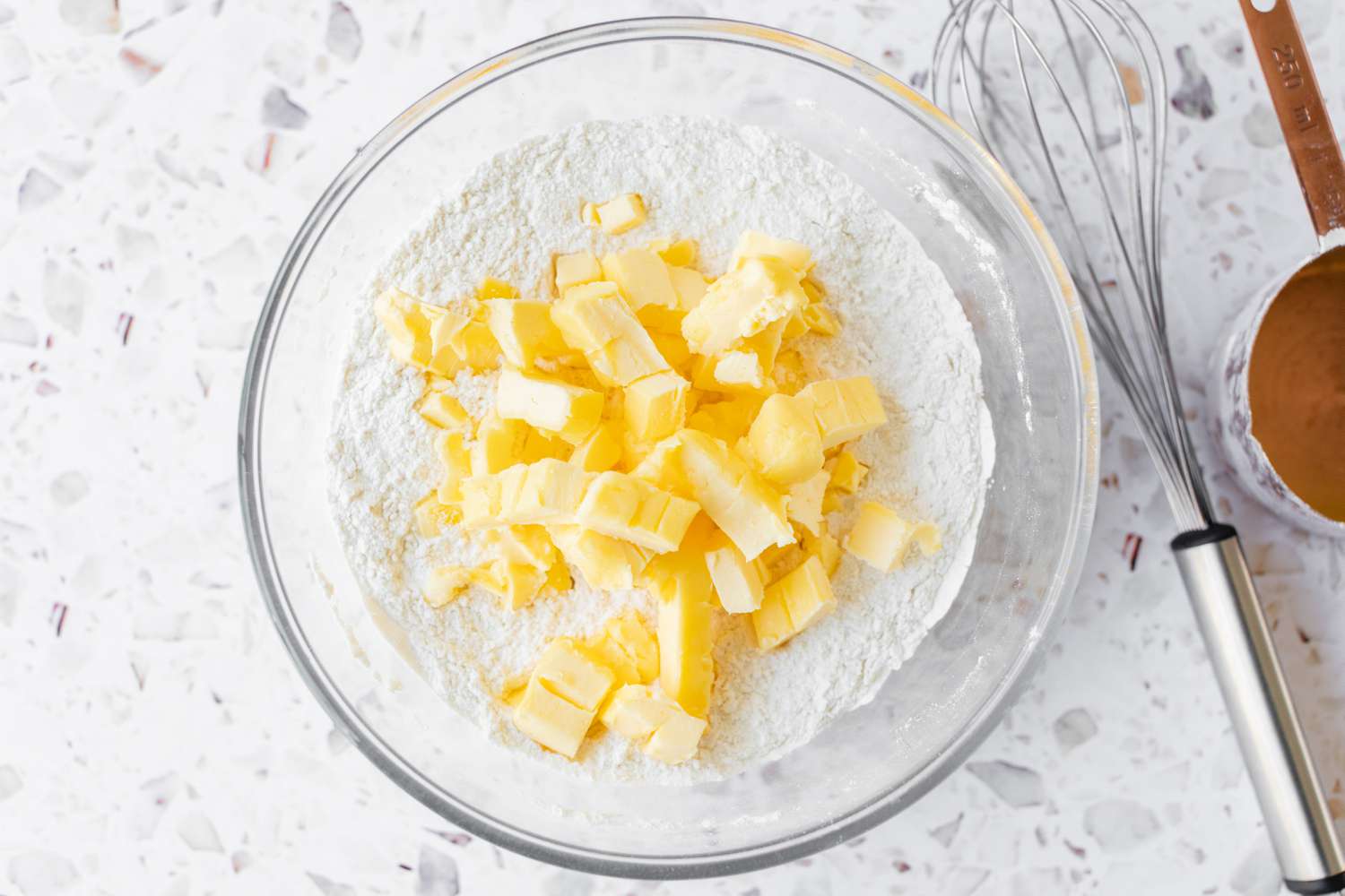 Cold Butter Cubes in a Bowl with Flour and Next to the Bowl a Whisk for Strawberry Shortcake Recipe
