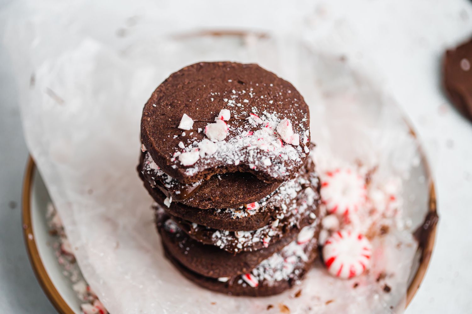 Overhead view of a stack of shortbread dipped in chocolate and peppermint on a platter with peppermints.
