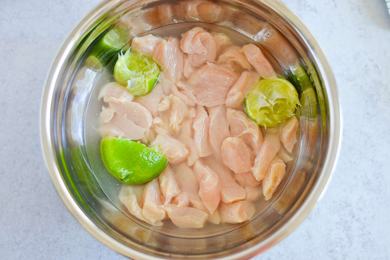 Limes Added to Chicken in Large Bowl for Rasta Pasta with Jerk Chicken