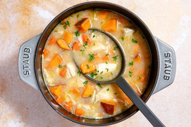 Overhead view of easy chicken stew in a gray dutch oven with a large serving spoon