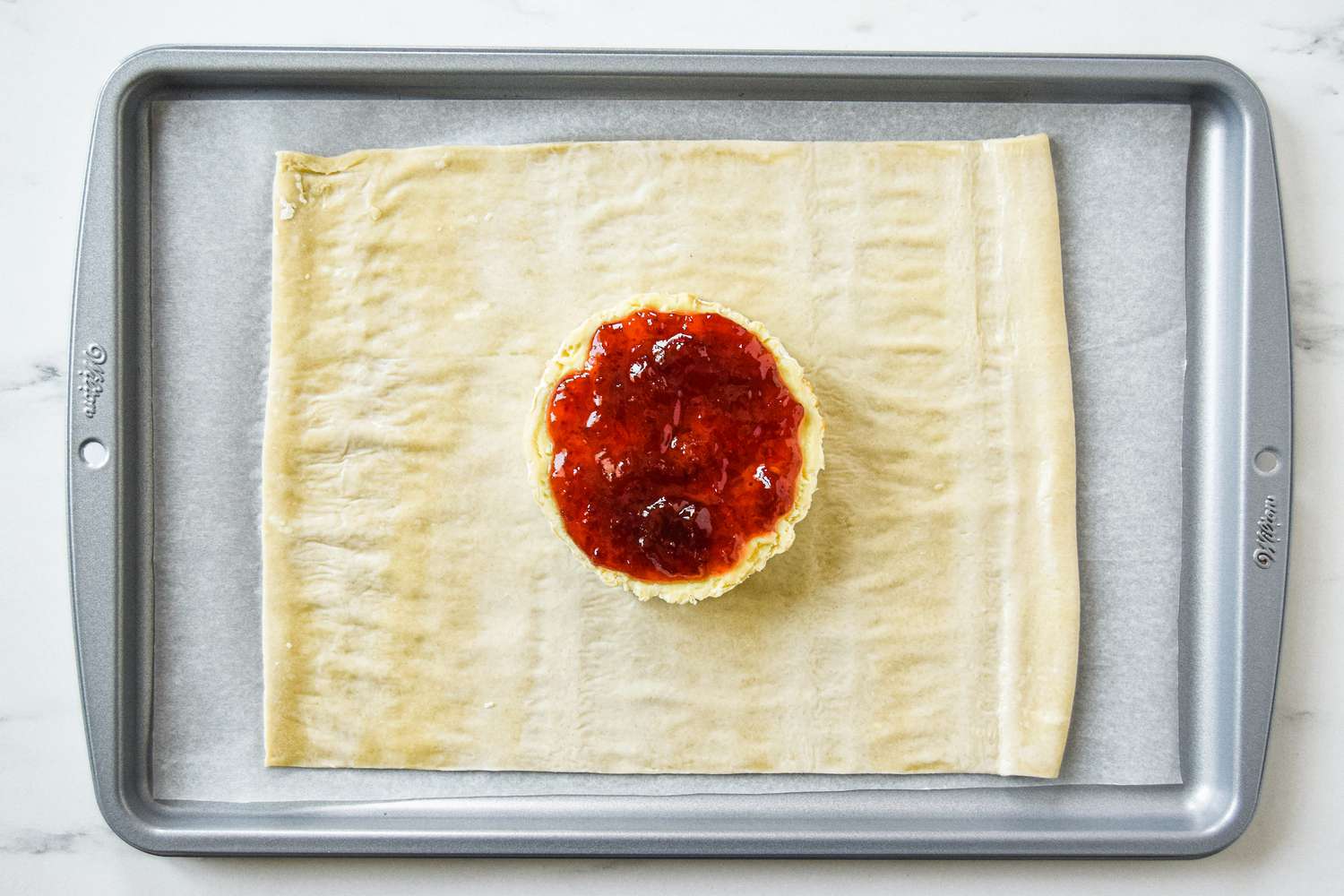 Jam on top of brie cheese set on puff pastry to make baked brie puff pastry