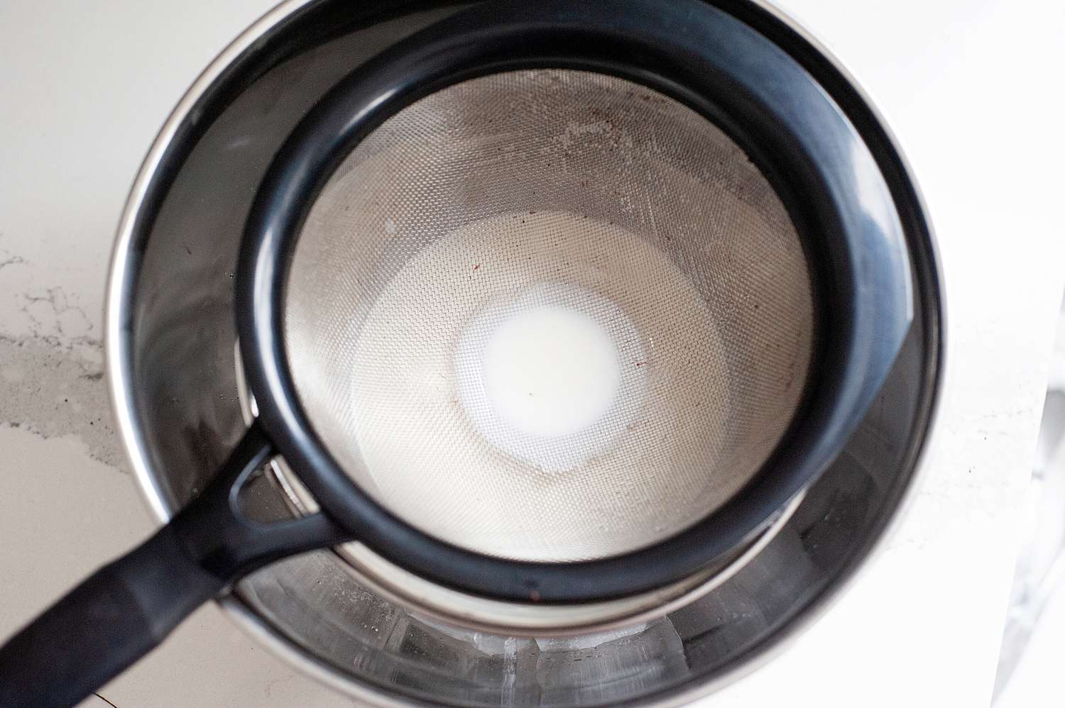 Strainer set over an ice bath to make mint chocolate chip ice cream..