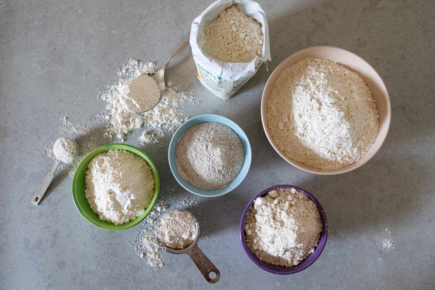 A bunch of colorful bowls with flour in them