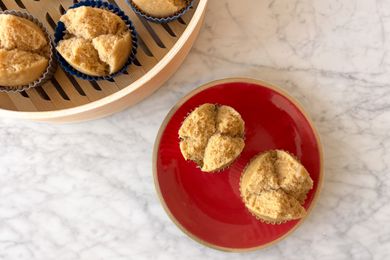 Overhead photo of two longevity cakes on a red plate with a bamboo steamer of steamed longevity cakes peeking in
