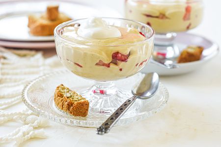 Two parfait glasses with a custard dessert topped with cream and layered with strawberries.