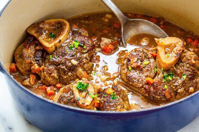 Ladling osso buco out of a dutch oven.