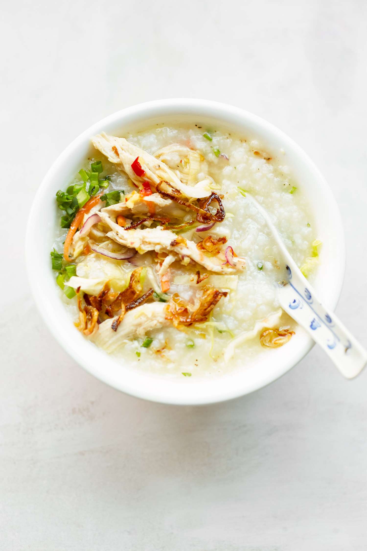 Chào Gá (Vietnamese Rice Porridge) Topped with Chicken in a Bowl with a Soup Spoon