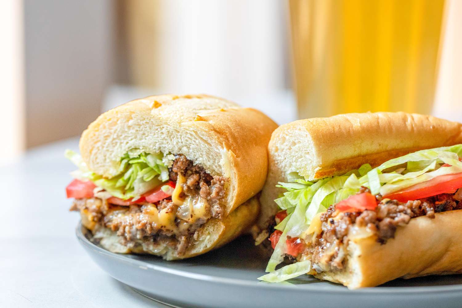 Two Halves of a Chopped Cheese Sandwich on a Plate 