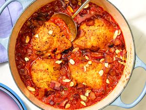 Overhead view of a blue dutch oven of finished Country Captain Chicken recipe on a white background