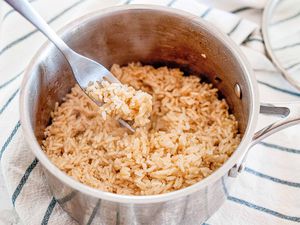 Pot with fork fluffing long grain brown rice that was cooked on a stovetop