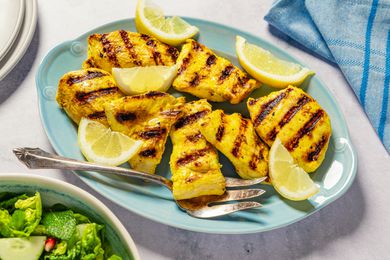 Grilled chicken pieces with lemon wedges on a plate