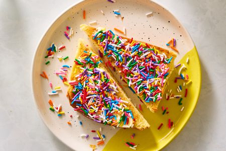 Two halves of toast covered in colorful sprinkles on a patterned plate