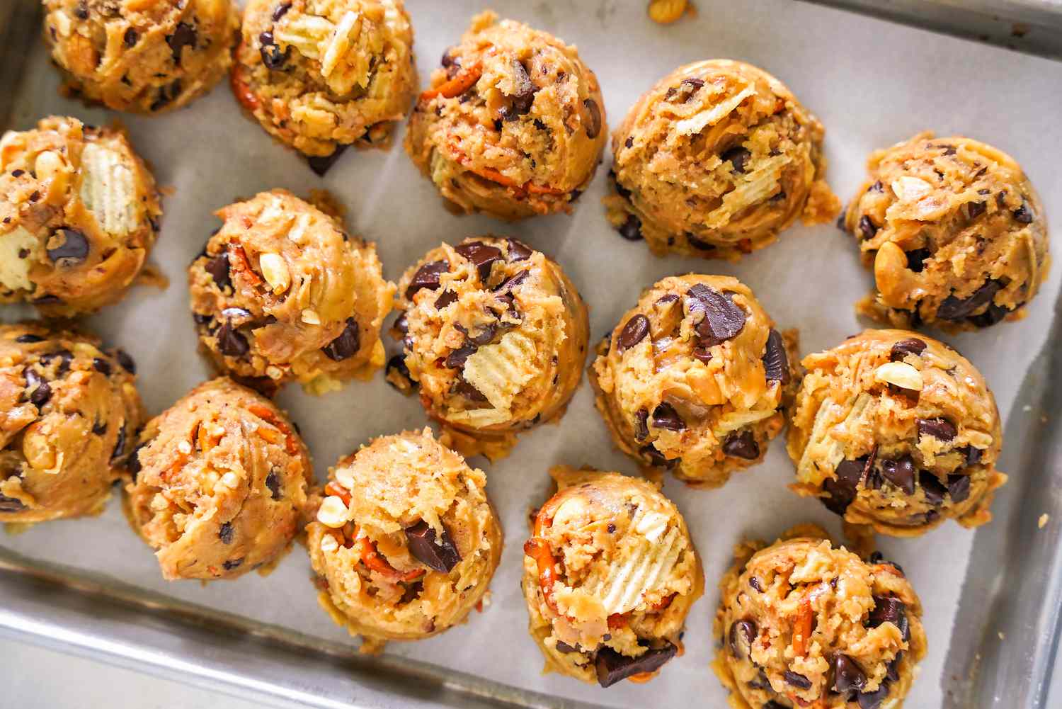 Tray With Equally Portioned Scoops of Kitchen Sink Cookie Dough on a Parchment Paper Lined Baking Tray