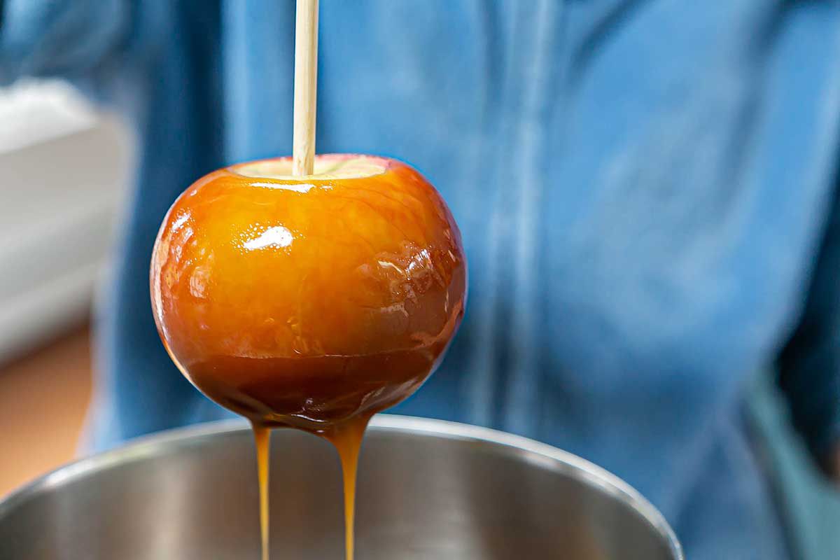 How to Make Caramel Apples apple on a stick with caramel dripping off it