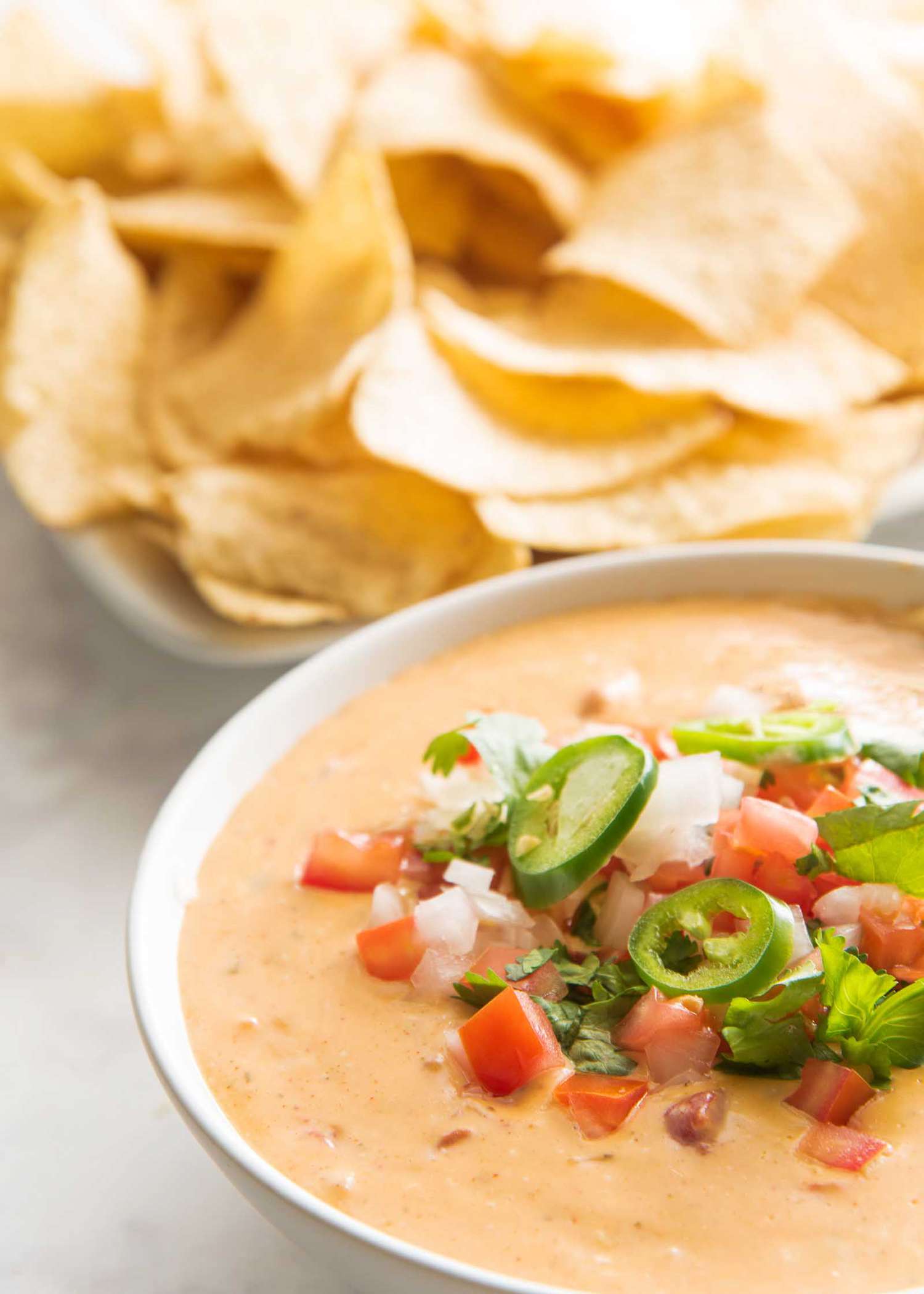 Gameday queso dip with a bowl of tortilla chips nearby.