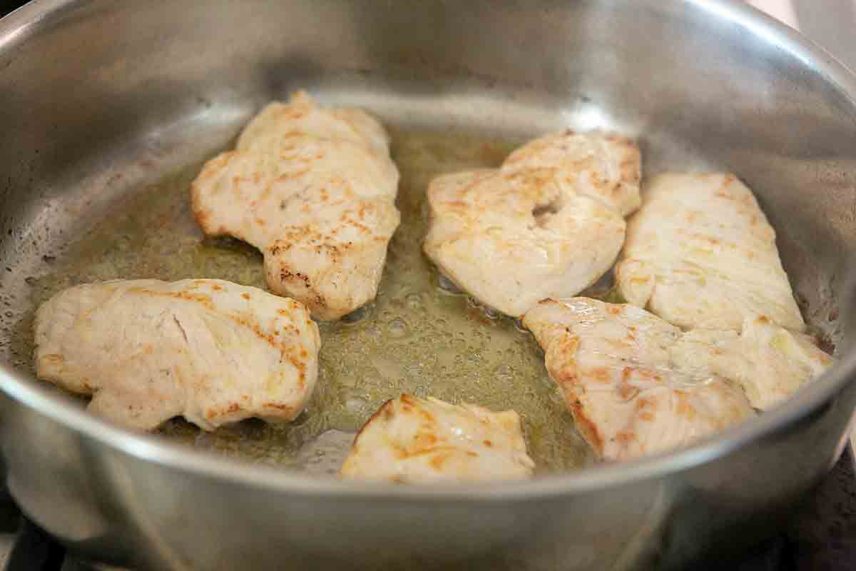 chicken breasts being cooked in pot for dijon chicken
