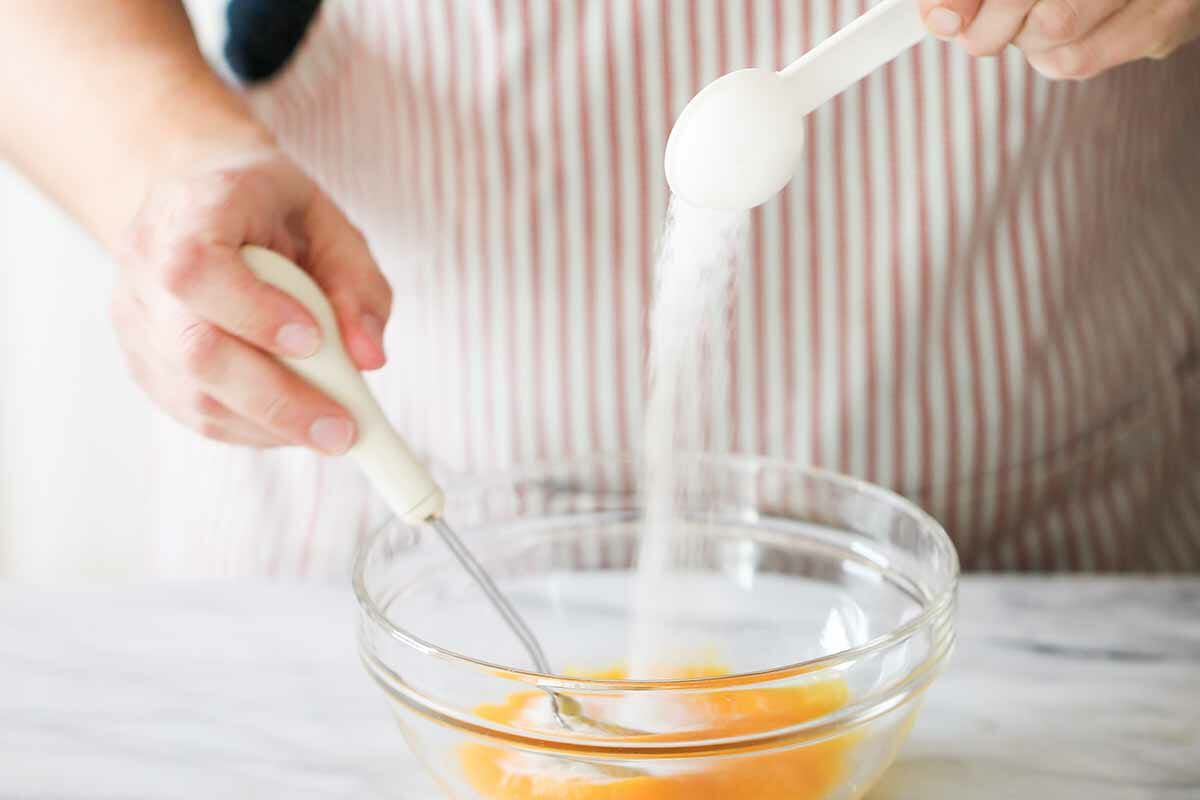Whisking sugar into the eggs in a glass bowl