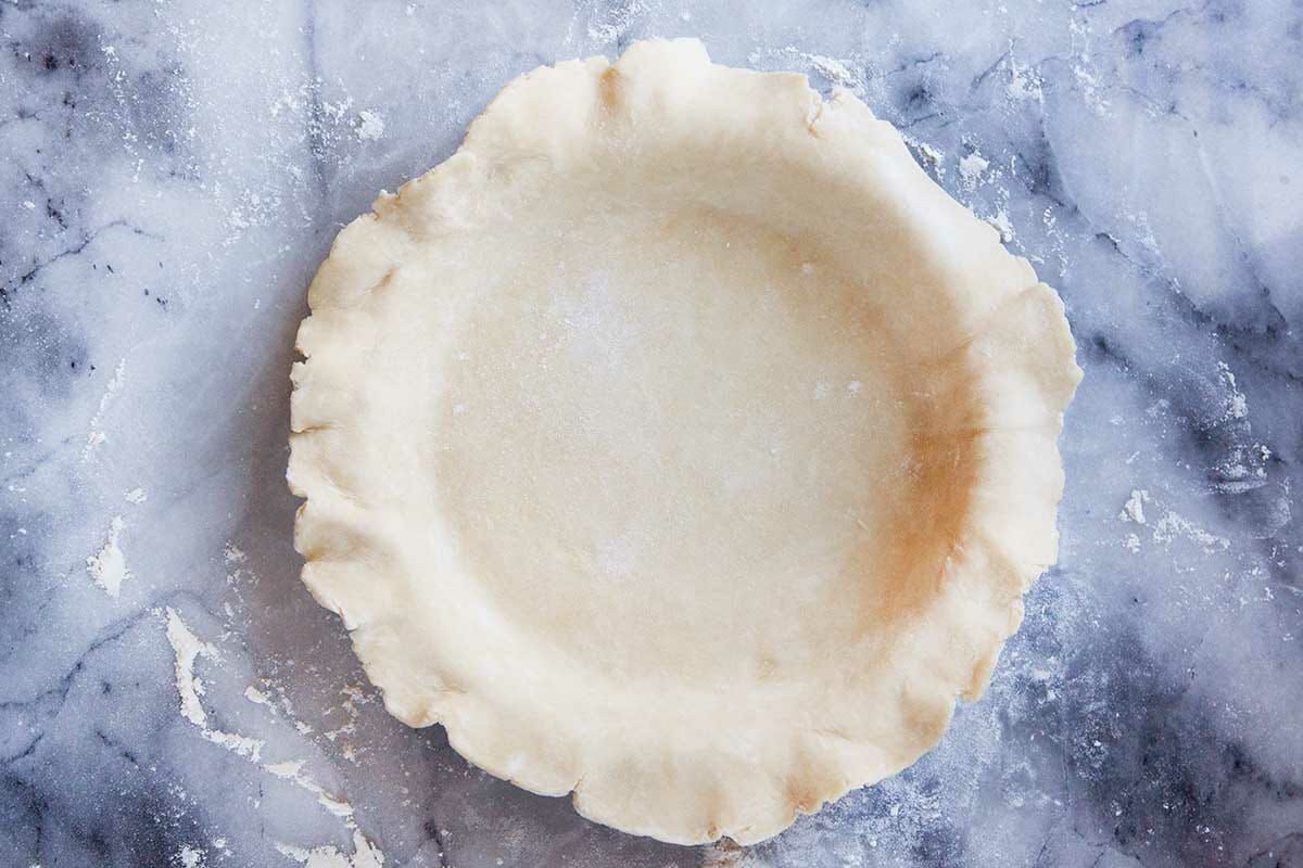 Easy chess pie crust unbaked and on a marble background.