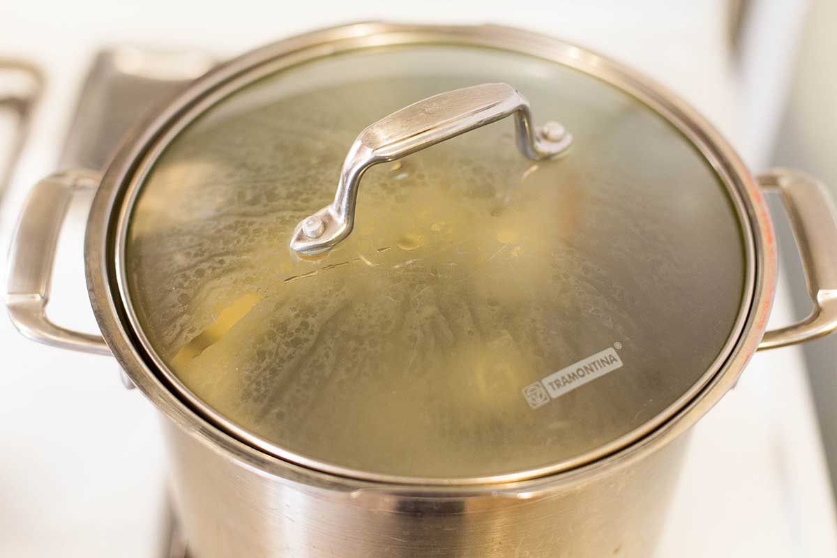 Matzo Balls being boiled in a pot with glass lid on top