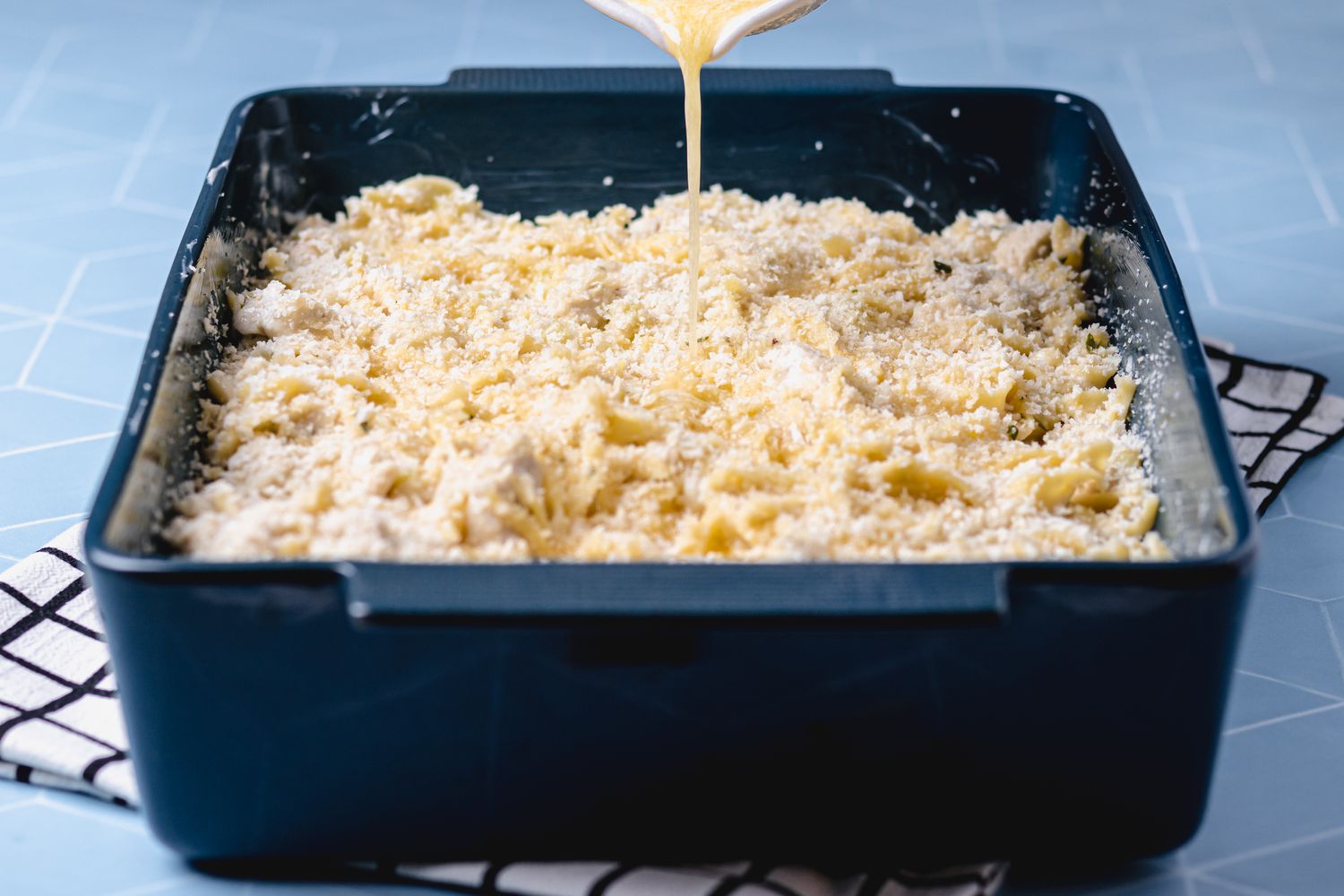 Drizzling butter over a recipe for leftover turkey in a baking dish
