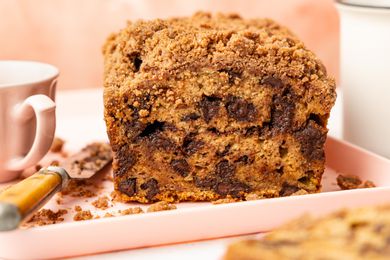 On a Platter, Chocolate Chip Banana Bread Cake Showcasing a Cross Section Cut, a Knife, and a Tea Cup