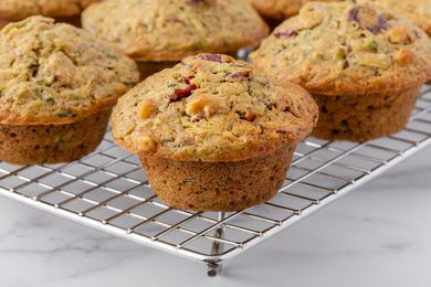 Zucchini muffins with walnuts and cranberries on cooling on a rack.