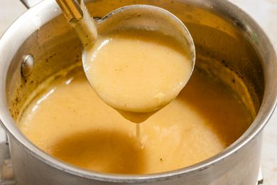 Angled view of a pot of 3-ingredient gravy with a ladle removing a serving