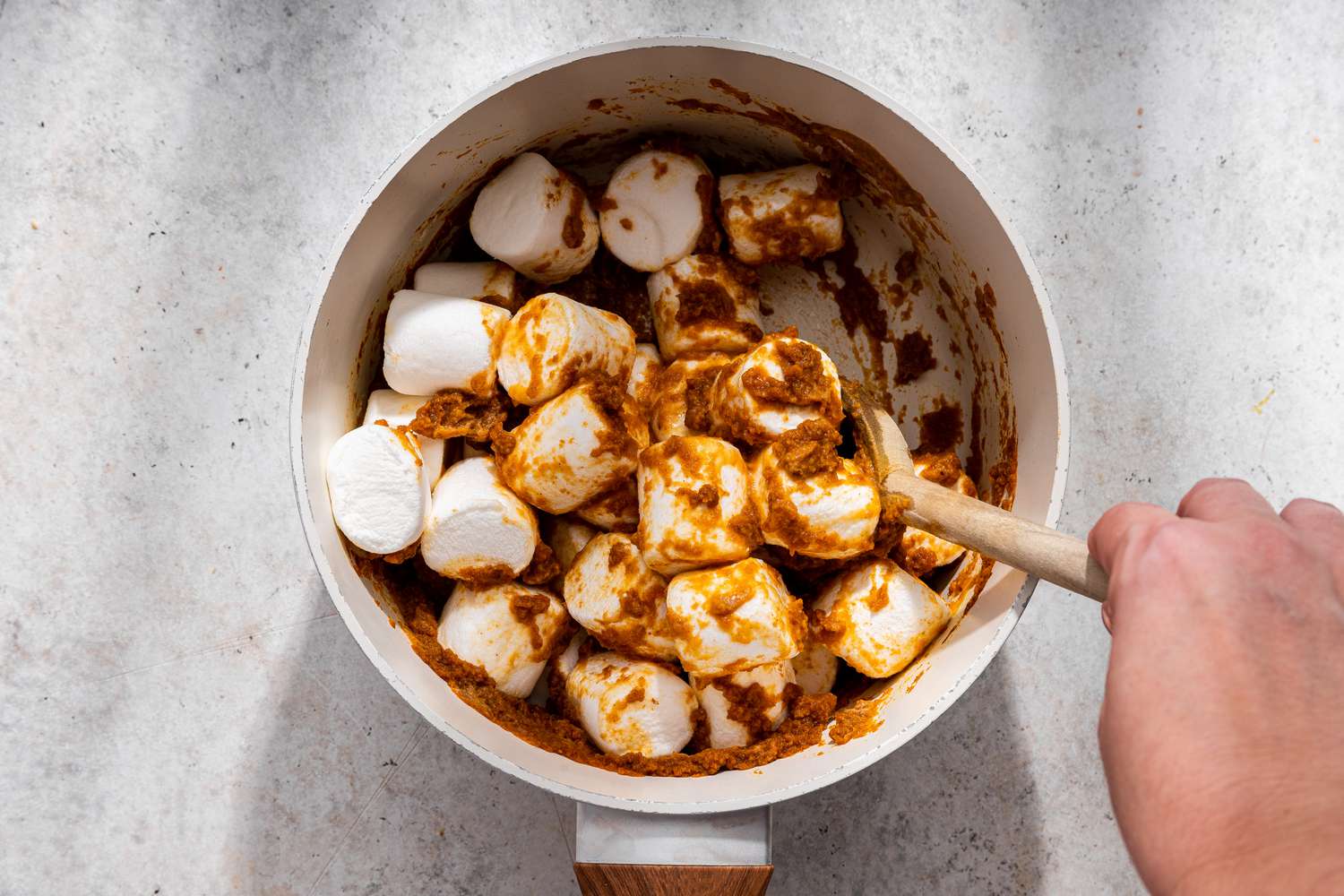 Jumbo marshmallows mixed with pumpkin puree mixture in a pan for no-bake pumpkin pie recipe