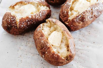 Three potatoes split open with butter and salt on the inside