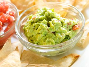 Guacamole and salsa in bowls with tortilla chips nearby