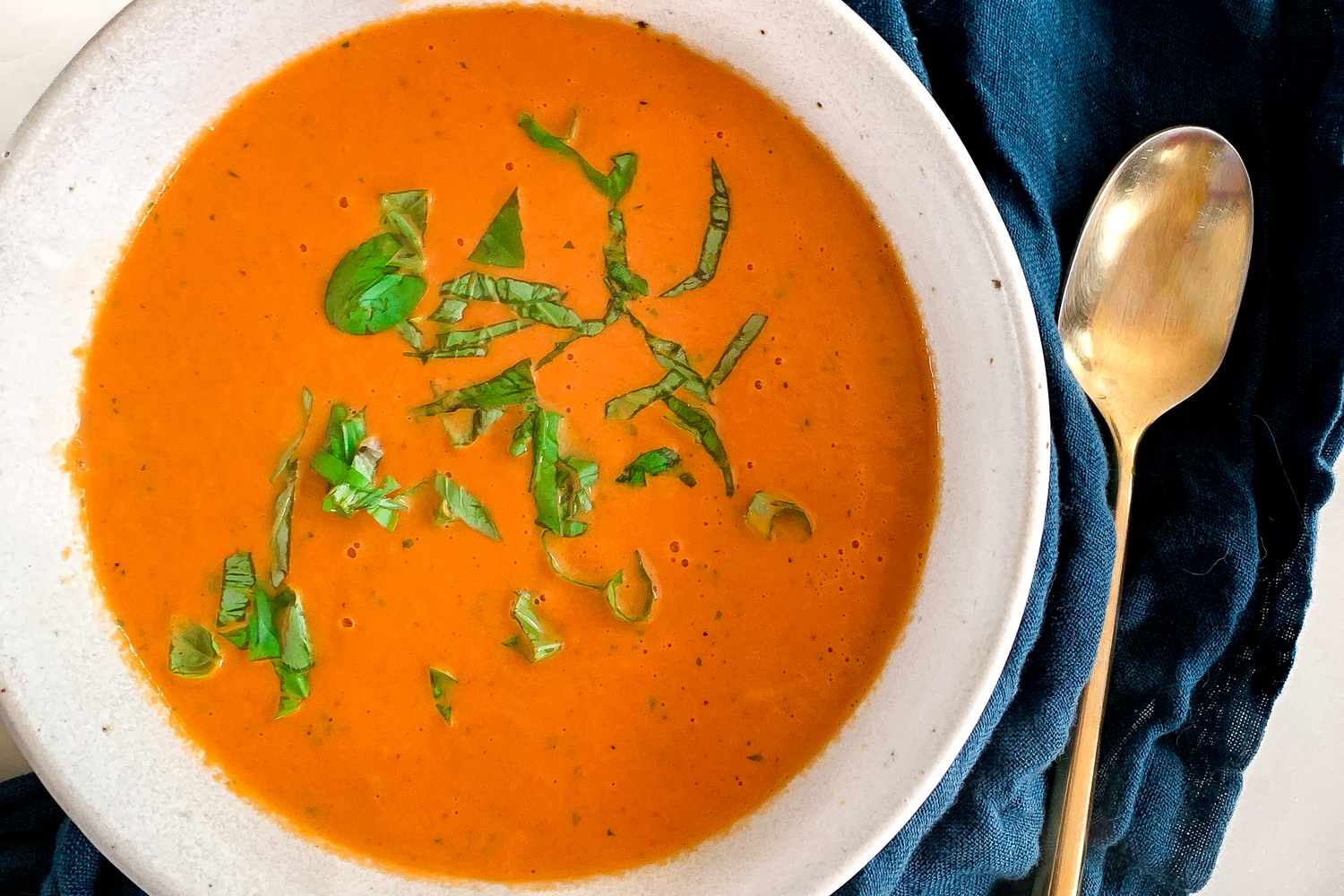 Bowl of Nordstrom soup next to a spoon and a blue table napkin