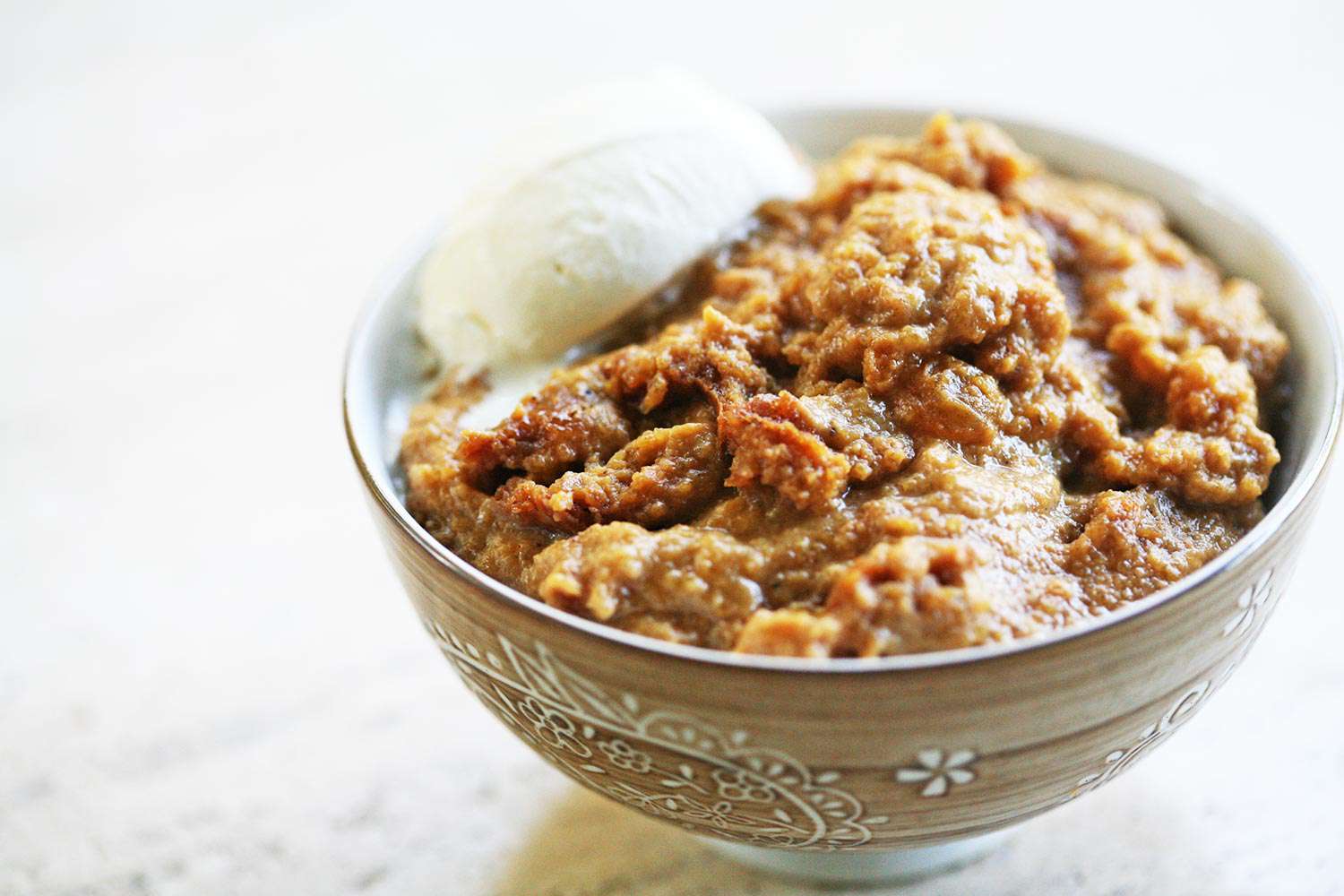 A bowl of Indian pudding with whipped cream on top