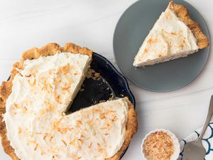 Overhead view of a homemade coconut cream pie with a slice removed and set on a plate to the right.
