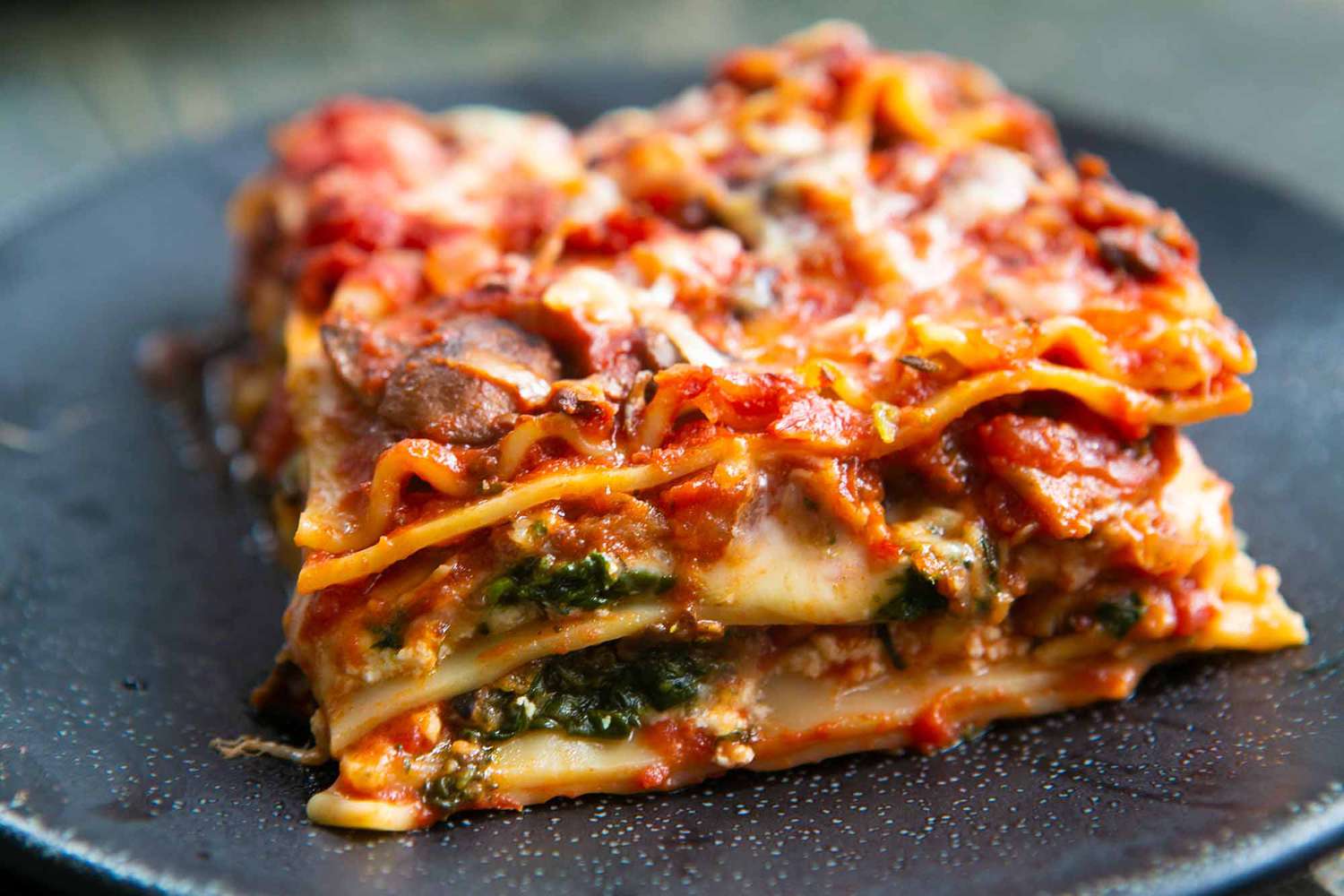 Slice of vegetarian lasagna on a black plate