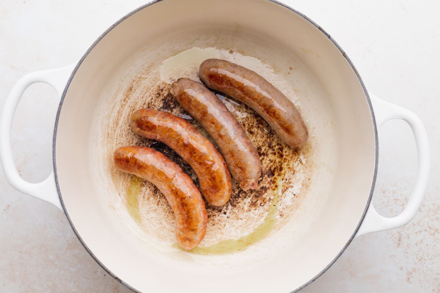 Sausages browning in a pan to make an Italian sausage peppers and onions recipe.