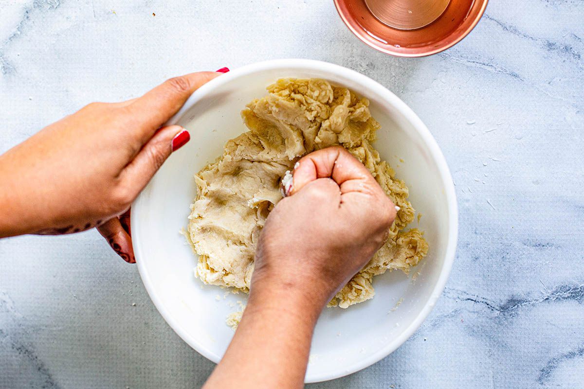 Woman kneeding the dough for samosas in a white bowl