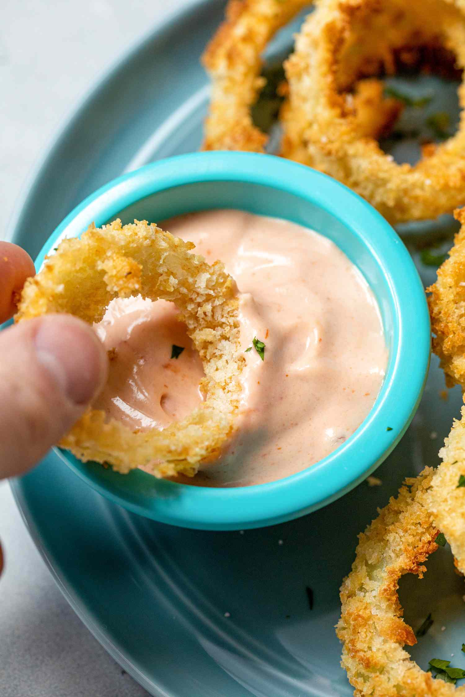 Dipping the Best Air Fryer Onion Rings in a sauce.
