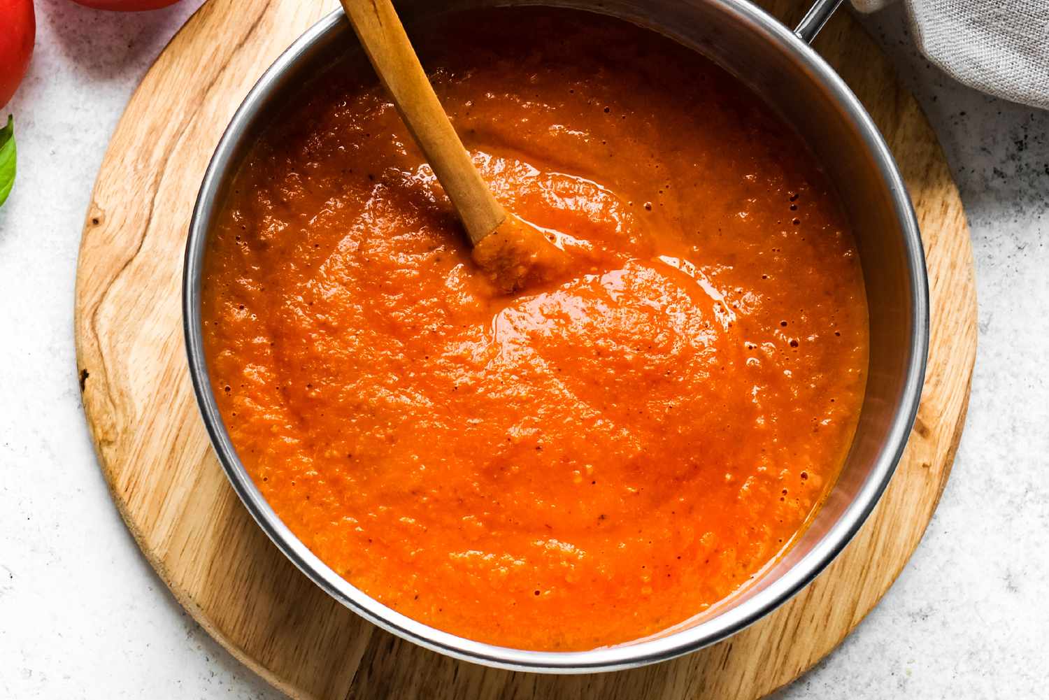 A pot of tomato soup with a wooden spoon stirring the soup